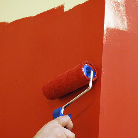 Måla vägg med röd målarfärg och roller.